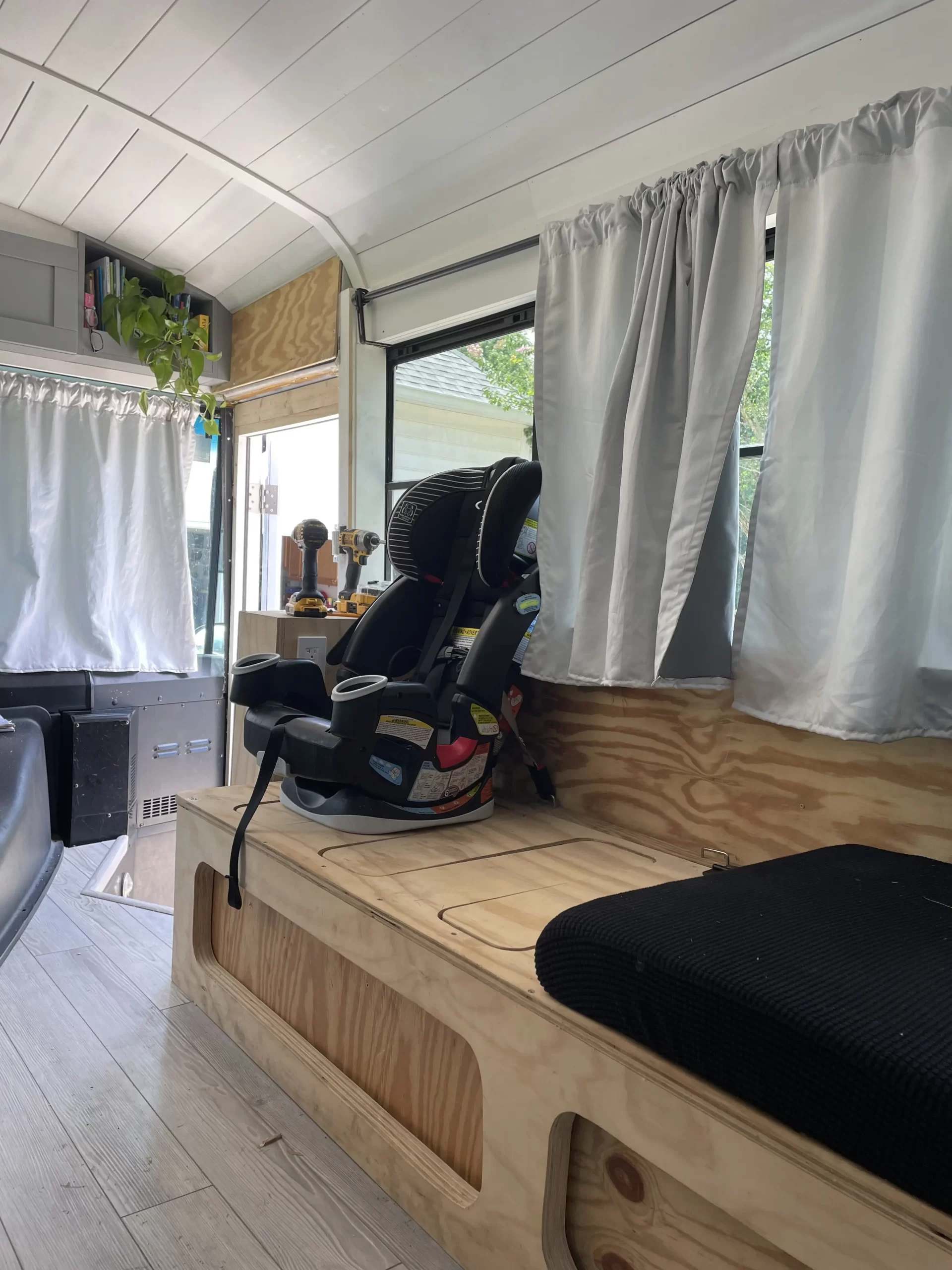 Car seat attached to mounting brackets in school bus conversion.